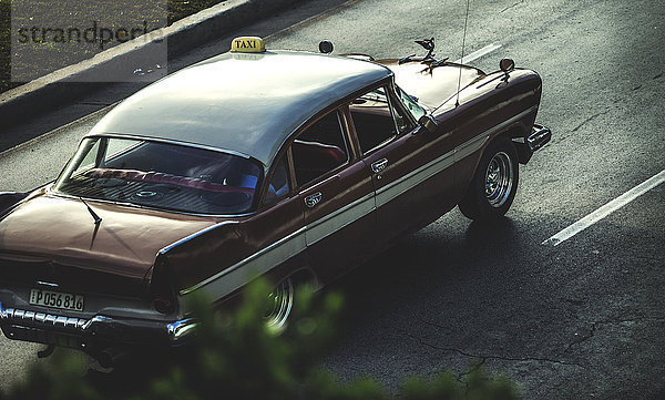 Hochwinkelaufnahme eines klassischen Autos aus den 1950er Jahren  das auf einer Straße fährt.