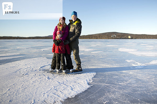 Eltern mit Tochter beim Schlittschuhlaufen auf dem zugefrorenen See