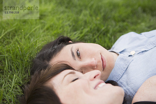 Ein gleichgeschlechtliches Paar  zwei Frauen  die im Gras liegen  sich zärtlich anschauen und sich entspannen.