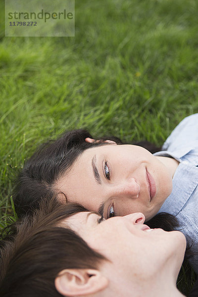 Ein gleichgeschlechtliches Paar  zwei Frauen  die im Gras liegen  sich zärtlich anschauen und sich entspannen.