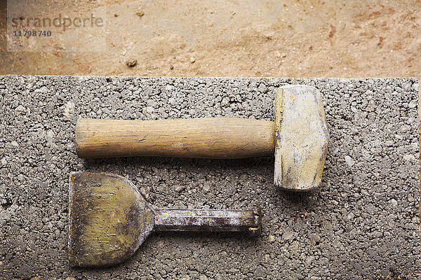 Nahaufnahme von Hammer und Meißel auf einer Betonplatte.