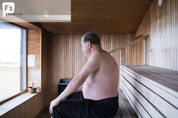 Älterer Mann sitzt in der Sauna