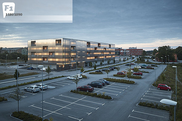 Modernes Wohngebäude und Parkplatz in der Abenddämmerung