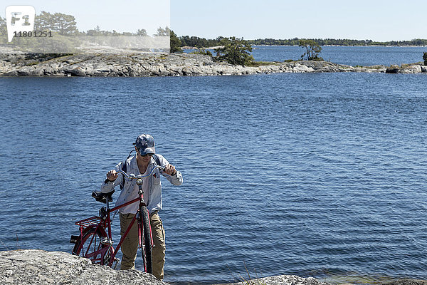 Mann mit Fahrrad am Wasser