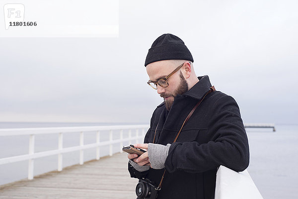 Mann auf Pier mit Smartphone