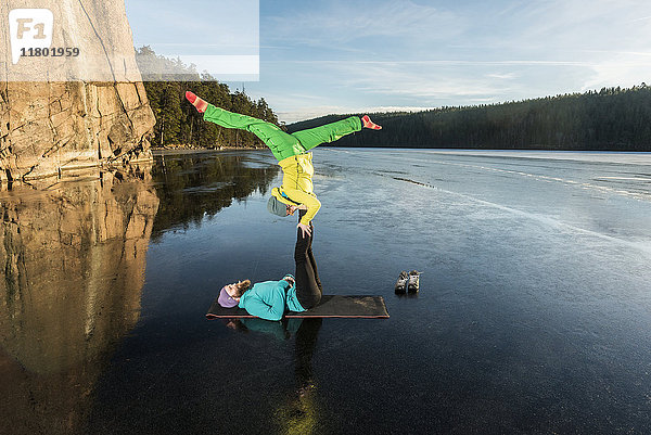 Pärchen beim Yoga auf gefrorenem See