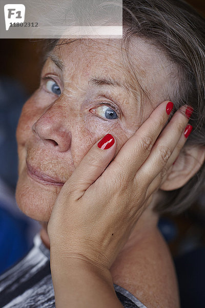 Hand einer Frau berührt das Gesicht einer älteren Frau