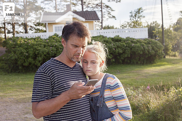 Vater mit Tochter schaut auf Handy