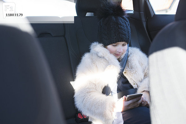 Mädchen mit Mobiltelefon im Auto sitzend