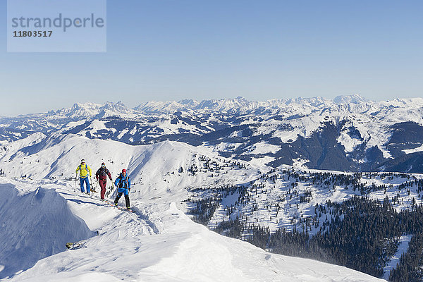 Skifahrer  die auf dem Grat eines Schneebergs laufen