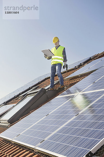 Ingenieur auf dem Dach  der die Sonnenkollektoren kontrolliert