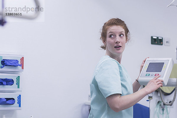 Weibliche Krankenschwester schaut bei der Bedienung medizinischer Geräte über die Schulter