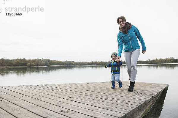 Mutter und Sohn gehen auf einem Holzsteg über den See