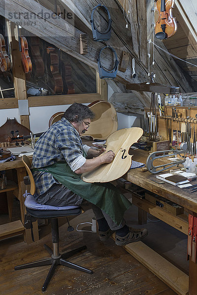 Handwerker bei der Arbeit an einer Geige in der Werkstatt