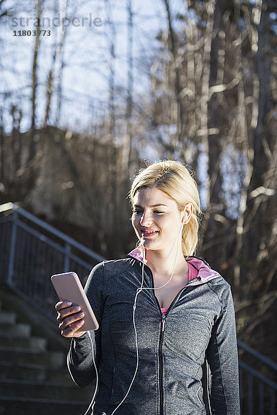 Frau in Sportkleidung hört Musik auf einem Smartphone