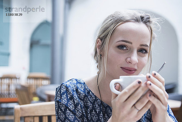 Nahaufnahme einer jungen Frau  die lächelnd eine Kaffeetasse hält