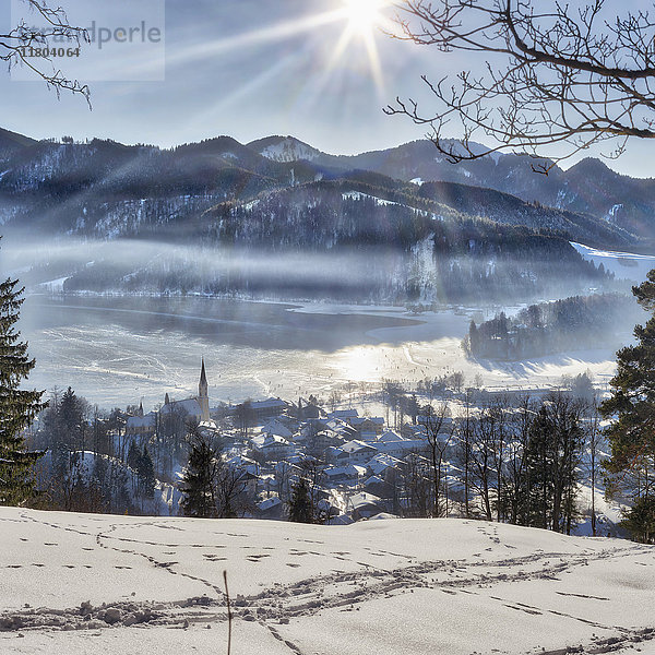 Schneebedeckte Stadt und Berg bei Sonnenaufgang