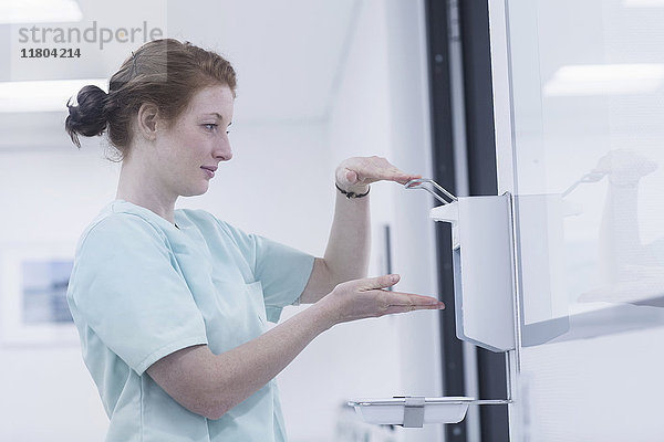 Seitenansicht einer Krankenschwester beim Desinfizieren der Hände