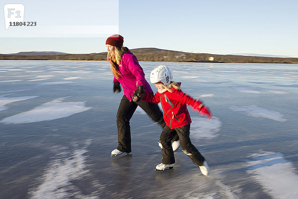 Mutter und Tochter beim Schlittschuhlaufen auf einem zugefrorenen See