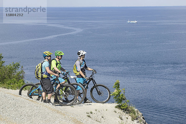 Ältere Biker schauen auf das Meer  während sie am Rand einer Klippe stehen