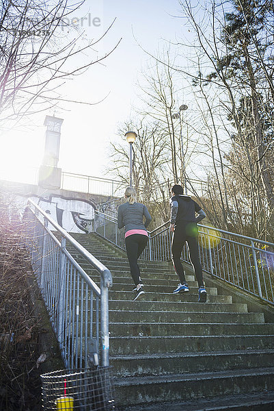 Mann und Frau joggen eine Treppe hinauf