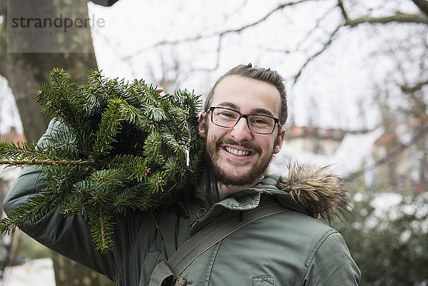 Porträt eines jungen Mannes mit Weihnachtsbaum
