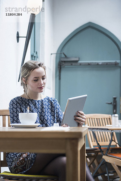 Junge Frau mit digitalem Tablet in einem Café