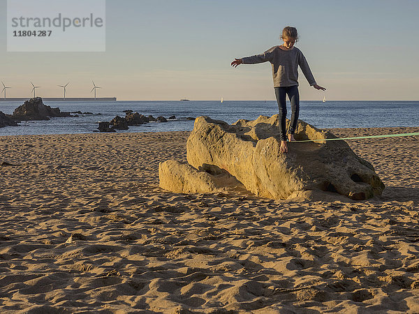 Mädchen balanciert auf einer Slackline an einem Strand in Nordspanien