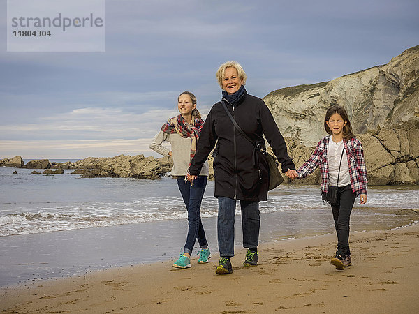 Großmutter geht mit Mädchen am Strand spazieren
