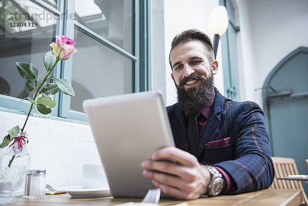 Intelligenter Geschäftsmann  der ein digitales Tablet benutzt  während er in einem Café sitzt