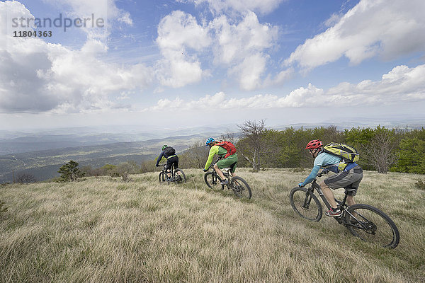 Radfahrer fahren Fahrräder durch Gras auf Berg