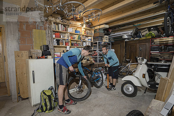 Männer  die in einer Garage ein Fahrrad aufpumpen