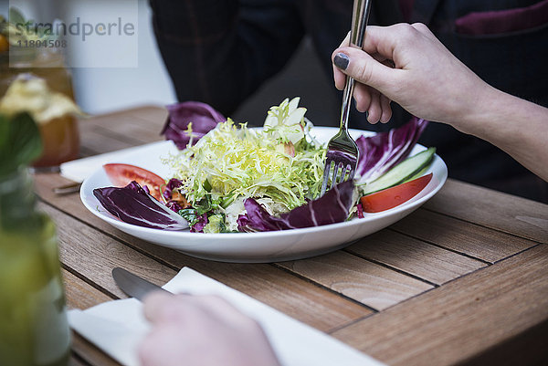 Ausgeschnittenes Bild einer Frau  die eine Gabel hält und Salat isst