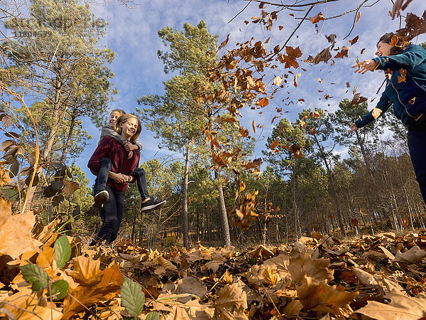 Mutter stehend und Teenager-Mädchen trägt Schwester huckepack im Wald
