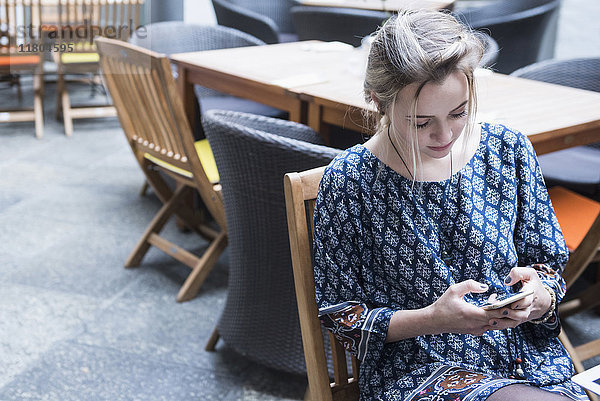Junge Frau schreibt eine SMS  während sie im Restaurant sitzt