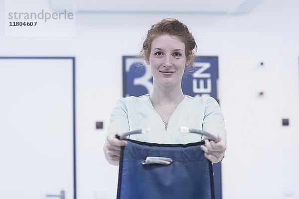 Porträt einer jungen Krankenschwester  die einen Körperschutz gegen Röntgenstrahlen hält