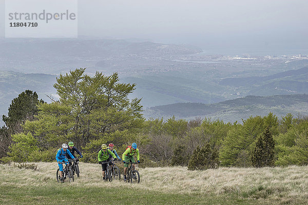 Ein Team von Radfahrern fährt mit dem Fahrrad im Gras auf einem Berg