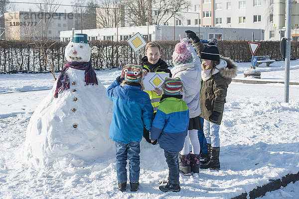 Mann unterrichtet Kinder mit Hilfe eines Pfeilzeichens in Verkehrssicherheit