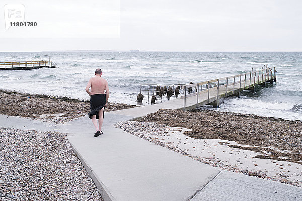 Mann geht auf der Strandpromenade spazieren