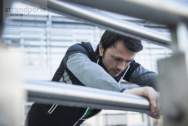 Mann in Sportkleidung entspannt sich nach dem Training auf einer Brücke