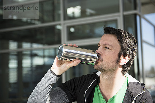 Mann in Sportkleidung trinkt Wasser nach dem Training