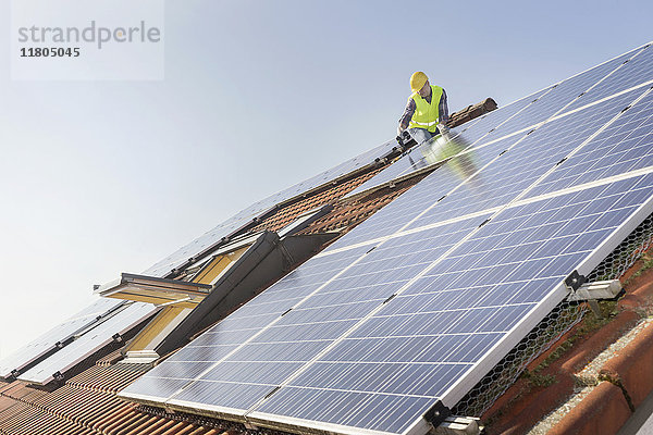 Ingenieur auf dem Dach bei der Installation von Sonnenkollektoren