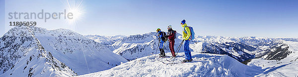 Drei Skifahrer stehen auf einem schneebedeckten Berg