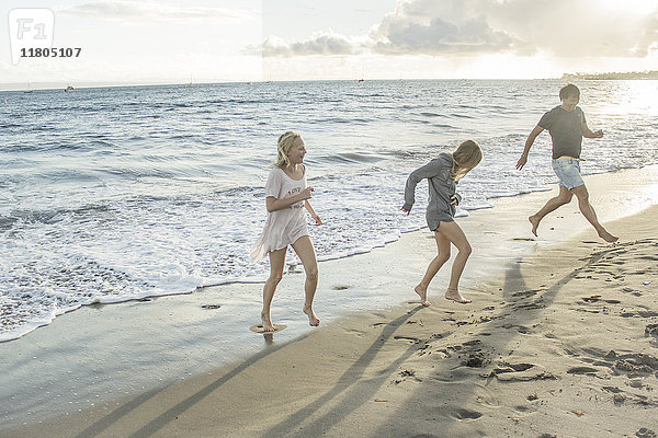 Vater mit Töchtern läuft am Strand