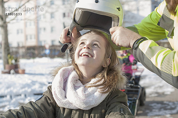 Mann hilft Mädchen beim Tragen eines Helms