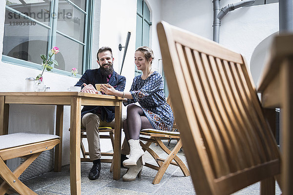 Lächelndes junges Paar benutzt Mobiltelefon in einem Café