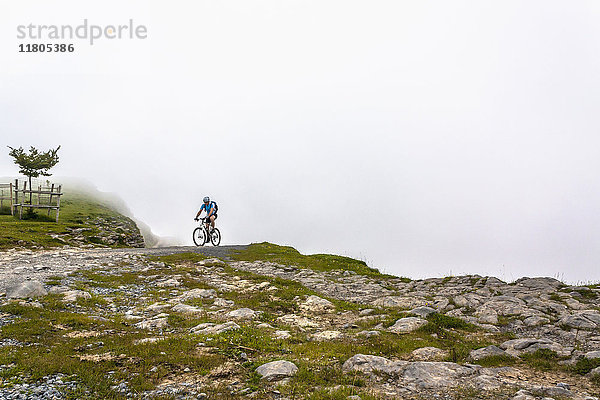 Mountainbiker auf unbefestigtem Weg an einem felsigen Abhang