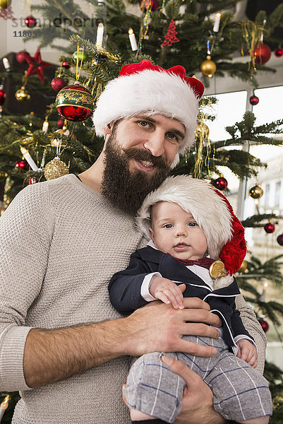 Vater hält kleinen Jungen an den Weihnachtsbaum