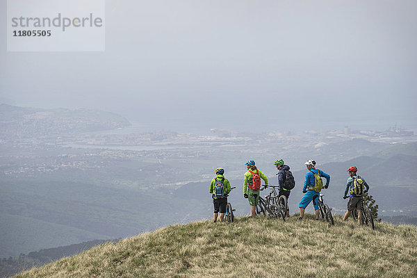 Mountainbiker betrachten die Aussicht  während sie auf dem Gipfel eines Berges stehen