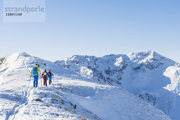 Rückansicht von Skifahrern  die auf einen Schneeberg steigen